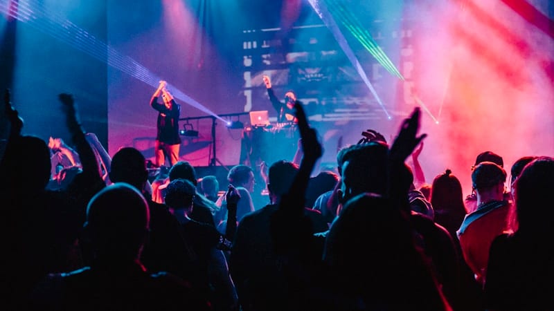 Pop tribute performers dancing and singing on stage under coloured lights